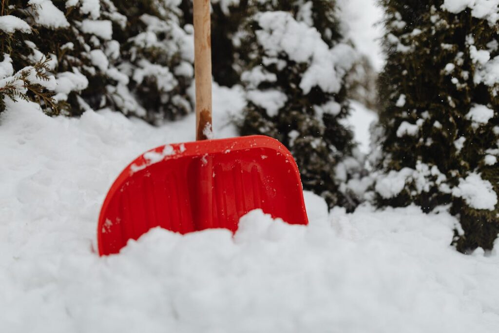 A red snow shovel is stuck in the snow