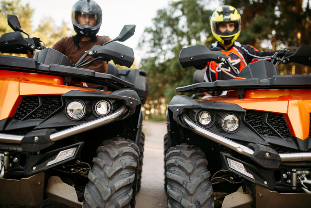 Two riders in helmets and equipment on quad bik